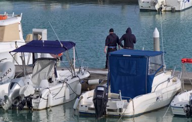 İtalya, Sicilya, Akdeniz, Marina di Ragusa (Ragusa Eyaleti); 20 Mart 2021, limanda insanlar ve motorlu tekneler - EDITORIAL