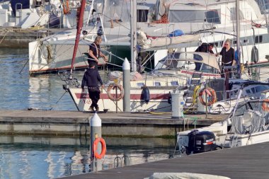 İtalya, Sicilya, Akdeniz, Marina di Ragusa (Ragusa Eyaleti); 28 Mart 2021, limandaki bir yelkenli ve lüks yatlarda yaşayan insanlar - EDITORIAL