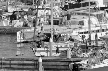 İtalya, Sicilya, Akdeniz, Marina di Ragusa (Ragusa Eyaleti); 28 Mart 2021, limanda yelkenli tekneleri ve lüks yatlarda insanlar - EDITORIAL