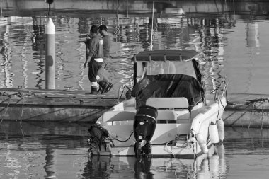 İtalya, Sicilya, Akdeniz, Marina di Ragusa (Ragusa Eyaleti); 30 Mart 2021, limanda insanlar ve motorlu tekneler - EDITORIAL