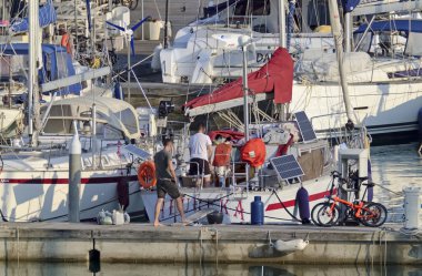 İtalya, Sicilya, Akdeniz, Marina di Ragusa (Ragusa Eyaleti); 30 Mart 2021, limandaki insanlar ve yelkenliler - EDITORIAL