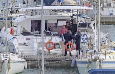 İtalya, Sicilya, Akdeniz, Marina di Ragusa (Ragusa ili); 31 Mart 2021, limandaki insanlar ve yelkenliler - EDITORIAL