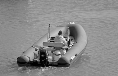 İtalya, Sicilya, Akdeniz, Marina di Ragusa (Ragusa Eyaleti); 1 Nisan 2021, limandaki kauçuk bir teknede adam - EDITORIAL