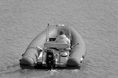 İtalya, Sicilya, Akdeniz, Marina di Ragusa (Ragusa Eyaleti); 1 Nisan 2021, limandaki kauçuk bir teknede adam - EDITORIAL