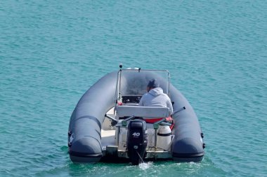 İtalya, Sicilya, Akdeniz, Marina di Ragusa (Ragusa Eyaleti); 1 Nisan 2021, limandaki kauçuk bir teknede adam - EDITORIAL