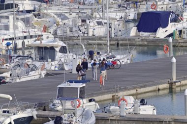 İtalya, Sicilya, Akdeniz, Marina di Ragusa (Ragusa Eyaleti); 3 Nisan 2021, limandaki insanlar, motorlu tekneler ve lüks yatlar - EDITORIAL