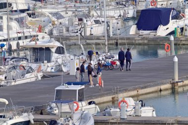 İtalya, Sicilya, Akdeniz, Marina di Ragusa (Ragusa Eyaleti); 3 Nisan 2021, limandaki insanlar, motorlu tekneler ve lüks yatlar - EDITORIAL