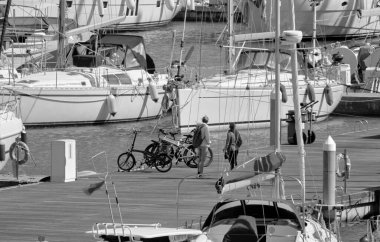 İtalya, Sicilya, Akdeniz, Marina di Ragusa (Ragusa ili); 7 Nisan 2021, limandaki insanlar ve lüks yatlar - EDITORIAL