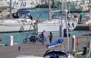 İtalya, Sicilya, Akdeniz, Marina di Ragusa (Ragusa ili); 7 Nisan 2021, limandaki insanlar ve lüks yatlar - EDITORIAL