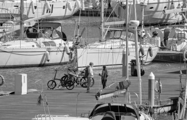 İtalya, Sicilya, Akdeniz, Marina di Ragusa (Ragusa ili); 7 Nisan 2021, limandaki insanlar ve lüks yatlar - EDITORIAL