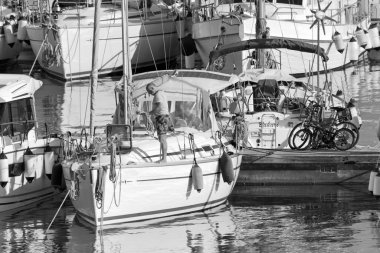 İtalya, Sicilya, Akdeniz, Marina di Ragusa (Ragusa Eyaleti); 14 Nisan 2021, limandaki bir yelkenli teknesi ve lüks yatlarda adam - EDITORIAL