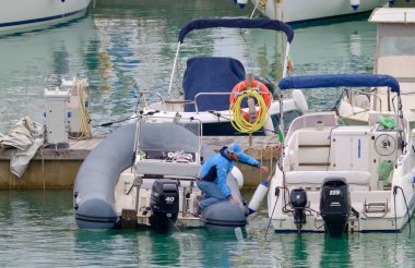 İtalya, Sicilya, Akdeniz, Marina di Ragusa (Ragusa Eyaleti); 23 Nisan 2021, limandaki bir kauçuk teknede adam - EDITORIAL