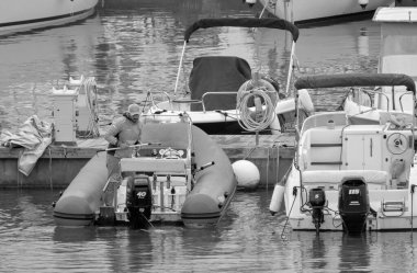 İtalya, Sicilya, Akdeniz, Marina di Ragusa (Ragusa Eyaleti); 23 Nisan 2021, limandaki bir kauçuk teknede adam - EDITORIAL