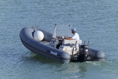 İtalya, Sicilya, Akdeniz, Marina di Ragusa (Ragusa Eyaleti); 28 Nisan 2021, limandaki kauçuk bir teknede adam - EDITORIAL