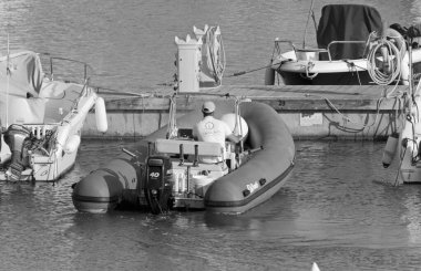 İtalya, Sicilya, Akdeniz, Marina di Ragusa (Ragusa Eyaleti); 28 Nisan 2021, limandaki kauçuk bir teknede adam - EDITORIAL