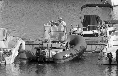 İtalya, Sicilya, Akdeniz, Marina di Ragusa (Ragusa Eyaleti); 28 Nisan 2021, limandaki kauçuk bir teknede adam - EDITORIAL