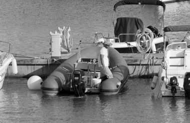 İtalya, Sicilya, Akdeniz, Marina di Ragusa (Ragusa Eyaleti); 28 Nisan 2021, limandaki kauçuk bir teknede adam - EDITORIAL