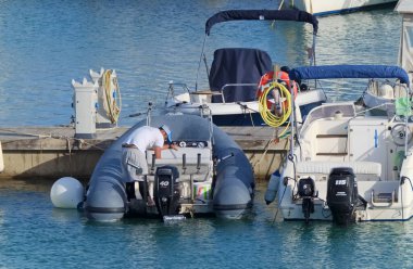 İtalya, Sicilya, Akdeniz, Marina di Ragusa (Ragusa Eyaleti); 28 Nisan 2021, limandaki kauçuk bir teknede adam - EDITORIAL