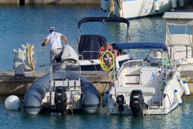 İtalya, Sicilya, Akdeniz, Marina di Ragusa (Ragusa Eyaleti); 28 Nisan 2021, limandaki kauçuk bir teknede adam - EDITORIAL