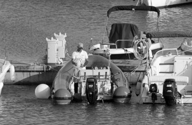 İtalya, Sicilya, Akdeniz, Marina di Ragusa (Ragusa Eyaleti); 28 Nisan 2021, limandaki kauçuk bir teknede adam - EDITORIAL