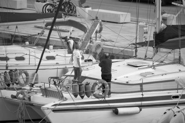 İtalya, Sicilya, Akdeniz, Marina di Ragusa (Ragusa Eyaleti); 4 Mayıs 2021, limandaki bir yelkenli ve lüks yatlarda erkekler - EDITORIAL