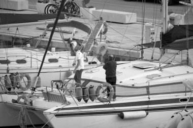 İtalya, Sicilya, Akdeniz, Marina di Ragusa (Ragusa Eyaleti); 4 Mayıs 2021, limandaki bir yelkenli ve lüks yatlarda erkekler - EDITORIAL