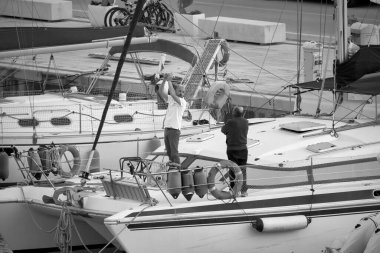 İtalya, Sicilya, Akdeniz, Marina di Ragusa (Ragusa Eyaleti); 4 Mayıs 2021, limandaki bir yelkenli ve lüks yatlarda erkekler - EDITORIAL