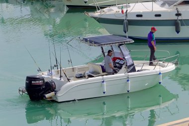 İtalya, Sicilya, Akdeniz, Marina di Ragusa (Ragusa Eyaleti); 6 Mayıs 2021, limanda bir motorlu tekne ve lüks yatlarda balıkçılar - EDITORIAL