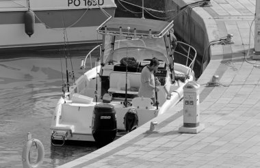 İtalya, Sicilya, Akdeniz, Marina di Ragusa (Ragusa Eyaleti); 6 Mayıs 2021, limanda bir motorlu tekne ve lüks yatlarda balıkçılar - EDITORIAL