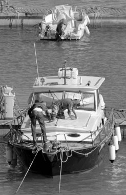 İtalya, Sicilya, Akdeniz, Marina di Ragusa (Ragusa Eyaleti); 12 Mayıs 2021, limanda lüks bir yat ve motorlu tekne kullanan erkekler - EDITORIAL