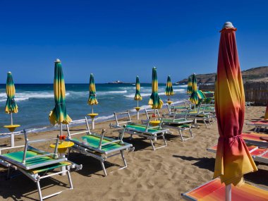 İtalya, Sicilya, İyon denizi, Portopalo di Capo Passero, plajda şezlonglar, arka planda Capo Passero adası.