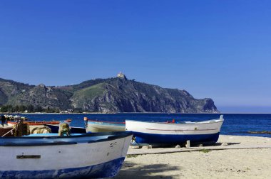 İtalya, Sicilya, Tindari, sahilde balıkçı tekneleri ve tepedeki Tindari Katedrali.