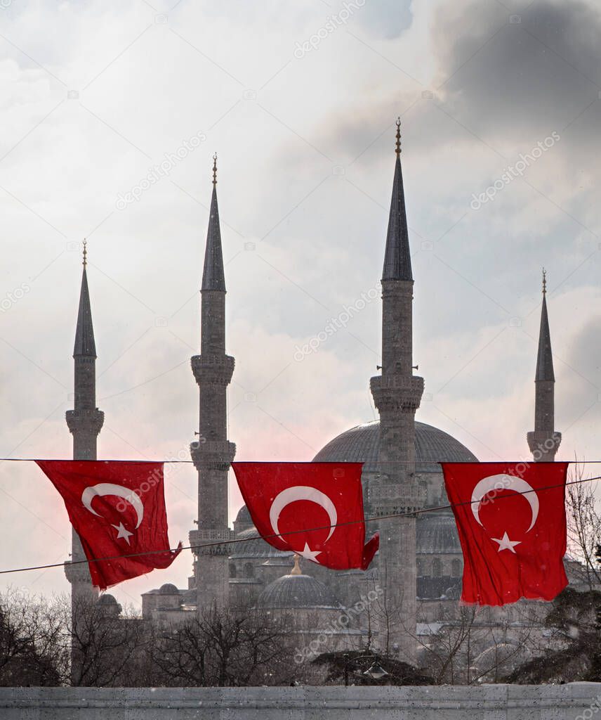 Turkey, Istanbul, Turkish flags and Sultanahmet Imperial Mosque, also known as the Blue Mosque,  while snowing (built in the 17th century by the architect Mehmet)