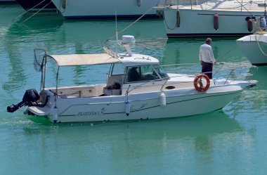 İtalya, Sicilya, Akdeniz, Marina di Ragusa (Ragusa Eyaleti); 4 Haziran 2021, limanda bir motorlu tekne ve lüks yatlarda erkekler - EDITORIAL