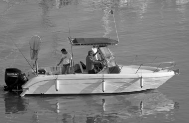 İtalya, Sicilya, Akdeniz, Marina di Ragusa (Ragusa Eyaleti); 13 Haziran 2021, limandaki bir motorlu teknede balıkçı - EDITORIAL