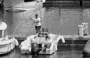 İtalya, Sicilya, Akdeniz, Marina di Ragusa (Ragusa ili); 17 Haziran 2021, limandaki bir motorlu teknede adam - EDITORIAL