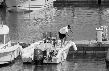 İtalya, Sicilya, Akdeniz, Marina di Ragusa (Ragusa ili); 17 Haziran 2021, limandaki bir motorlu teknede adam - EDITORIAL