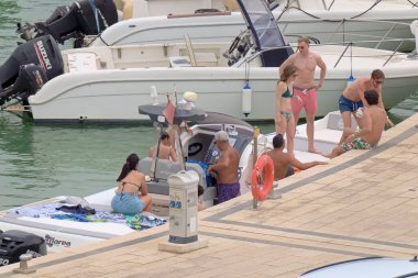 İtalya, Sicilya, Akdeniz, Marina di Ragusa (Ragusa ili); 26 Haziran 2021, büyük bir kauçuk bot ve limandaki lüks yatlarda yaşayan insanlar - EDITORIAL