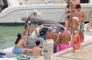 İtalya, Sicilya, Akdeniz, Marina di Ragusa (Ragusa ili); 26 Haziran 2021, büyük bir kauçuk bot ve limandaki lüks yatlarda yaşayan insanlar - EDITORIAL