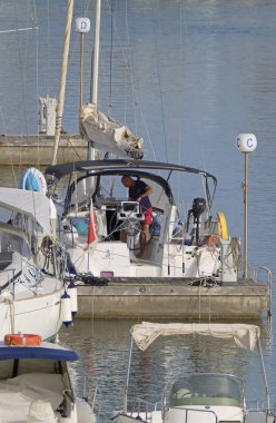 İtalya, Sicilya, Akdeniz, Marina di Ragusa (Ragusa Eyaleti); 28 Haziran 2021, limandaki bir yelkenli teknesinde adam - EDITORIAL