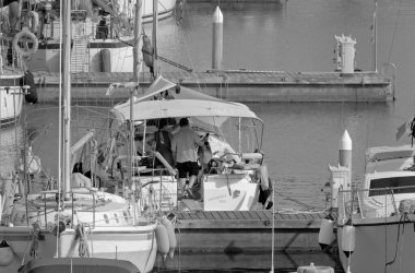 İtalya, Sicilya, Akdeniz, Marina di Ragusa (Ragusa Eyaleti); 1 Temmuz 2021, limandaki bir yelkenli ve lüks yatlarda yaşayan insanlar - EDITORIAL