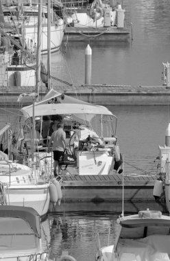 İtalya, Sicilya, Akdeniz, Marina di Ragusa (Ragusa Eyaleti); 1 Temmuz 2021, limandaki bir yelkenli ve lüks yatlarda yaşayan insanlar - EDITORIAL