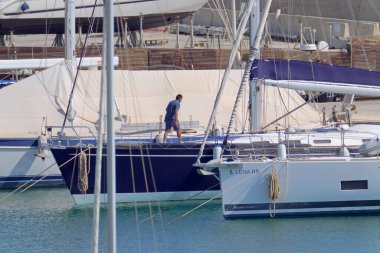 İtalya, Sicilya, Akdeniz, Marina di Ragusa (Ragusa Eyaleti); 2 Temmuz 2021, limandaki bir yelkenli teknesinde adam - EDITORIAL