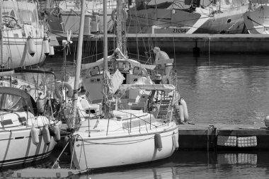 İtalya, Sicilya, Akdeniz, Marina di Ragusa (Ragusa Eyaleti); 10 Temmuz 2021, limandaki bir yelkenli teknesinde adam - EDITORIAL