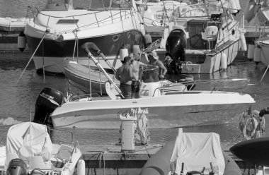 İtalya, Sicilya, Akdeniz, Marina di Ragusa (Ragusa Eyaleti); 10 Temmuz 2021, limanda bir motorlu tekne ve lüks yatlarda erkekler - EDITORIAL