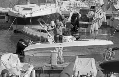 İtalya, Sicilya, Akdeniz, Marina di Ragusa (Ragusa Eyaleti); 10 Temmuz 2021, limanda bir motorlu tekne ve lüks yatlarda erkekler - EDITORIAL