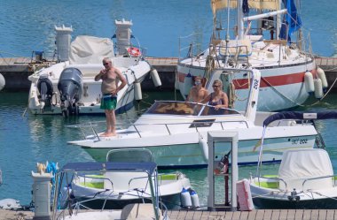 İtalya, Sicilya, Akdeniz, Marina di Ragusa (Ragusa ili); 11 Temmuz 2021, limandaki bir motorlu tekne ve lüks yatlarda yaşayan insanlar - EDITORIAL