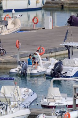 Italy, Sicily, Mediterranean Sea, Marina di Ragusa (Ragusa Province); 13 July 2021, people on a rubber boat and luxury yachts in the port - EDITORIAL