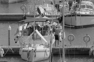 İtalya, Sicilya, Akdeniz, Marina di Ragusa (Ragusa Eyaleti); limanda insanlar ve yelkenliler 