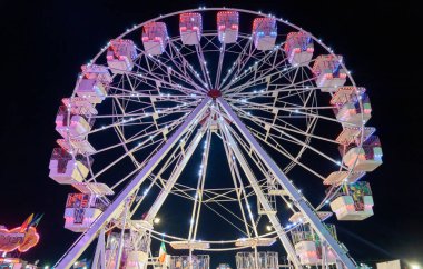 İtalya, Sicilya, Marina di Ragusa (Ragusa Eyaleti), 20 Temmuz 2021, bir lunaparkta geceleyin atlıkarıncalı insanlar